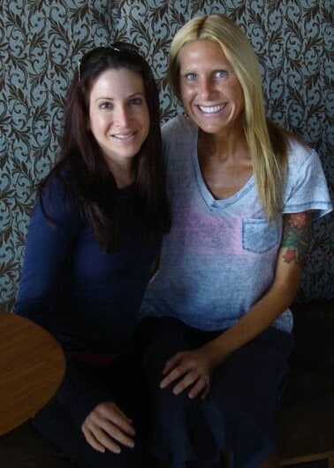 Two women with arms around one another smiling