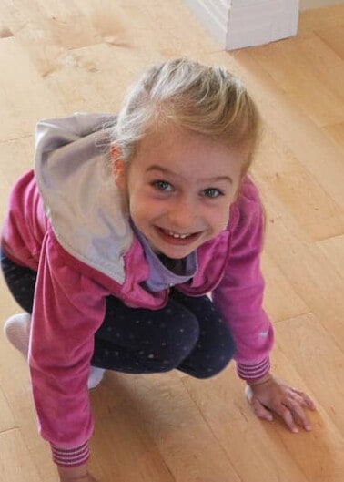 Young girl squatting on floor smiling