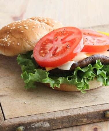 open hamburger with tomatoes, mushroom, cheese, and lettuce