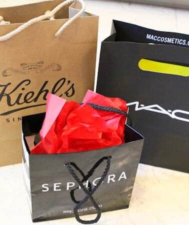 Three branded shopping bags from kiehl's, mac cosmetics, and sephora, with one showing tissue paper.