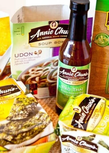 Assortment of annie chun's asian food products including soup bowls, sauce, and brown rice noodles.