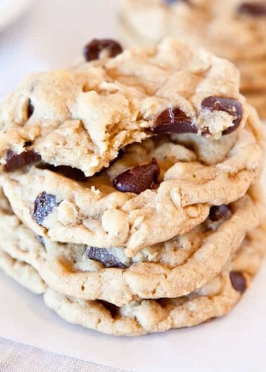 A stack of chocolate chip cookies on a white surface.