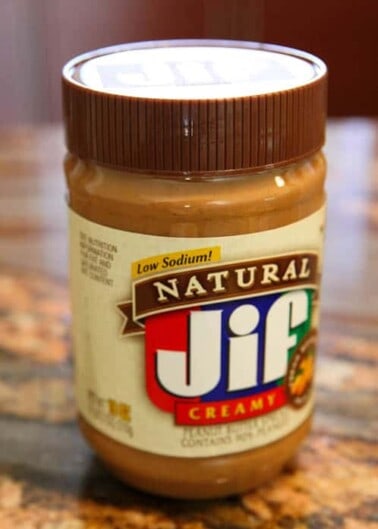 Jar of jif creamy peanut butter with a low sodium label on a countertop.