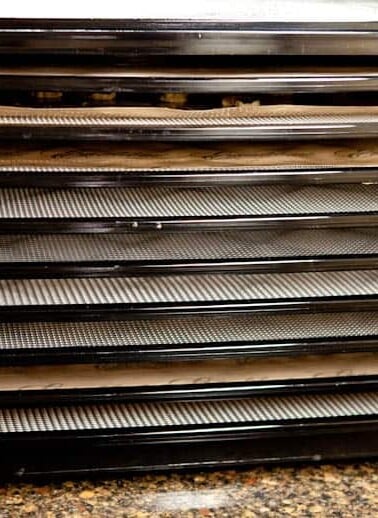 A food dehydrator with multiple trays on a kitchen counter.