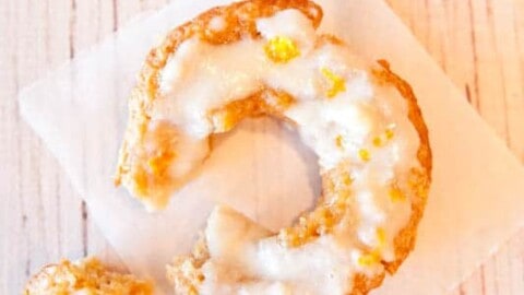 Glazed old-fashioned donut with a bite taken out, displayed on a white napkin.