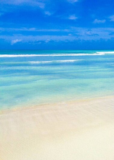 Tranquil beach with clear turquoise waters under a blue sky.