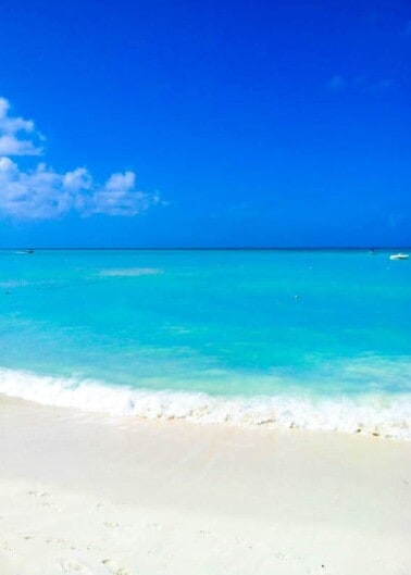 Tropical beach with clear turquoise waters and blue sky.