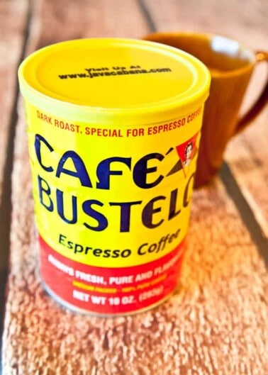 A café bustelo espresso coffee can sitting on a wooden surface.