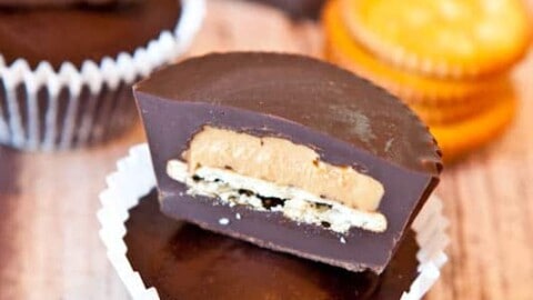Chocolate peanut butter cups with a section cut out to reveal the peanut butter filling.