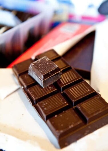 A close-up of a bar of dark chocolate with one piece broken off.