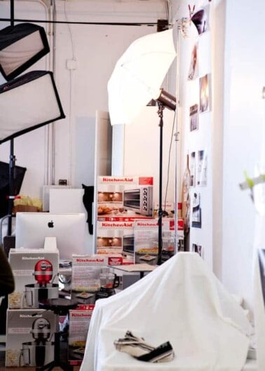 Photography studio setup with lighting equipment, covered furniture, and product packaging on display.