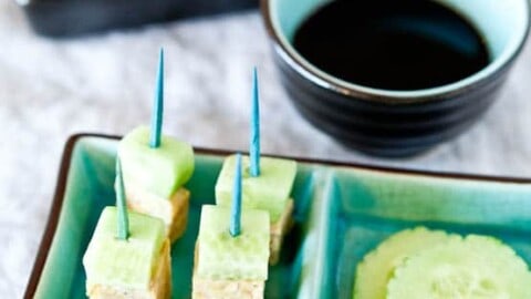 Cucumber and tofu bites with toothpick skewers served with soy sauce.