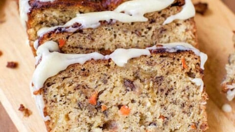 Sliced carrot cake loaf with cream cheese frosting on a wooden board.