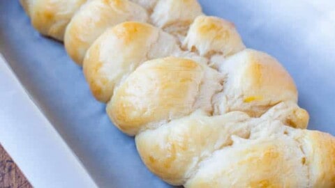 A freshly baked braided loaf of bread in a baking tray lined with parchment paper.