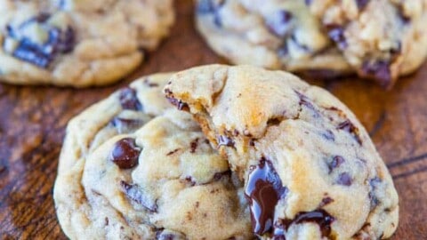 Freshly baked chocolate chip cookies on a wooden surface.