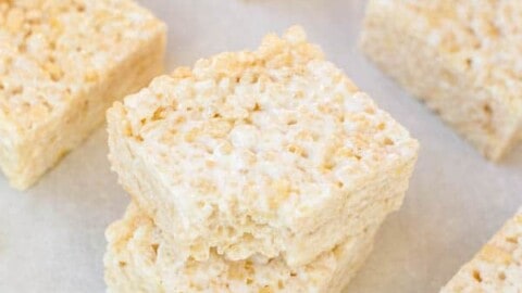 Homemade rice crispy treats stacked on parchment paper.