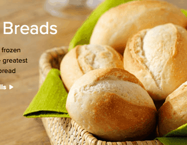 A selection of baked artisan dinner rolls presented on a green cloth with the caption "artisan breads.