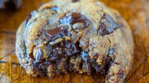 Freshly baked chocolate chip cookie on a wooden surface.