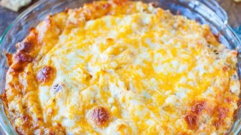 Baked cheesy dip served in a glass dish with crackers on the side.