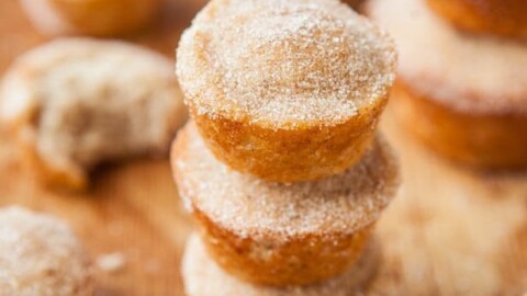 Stack of sugared doughnuts on a wooden surface.