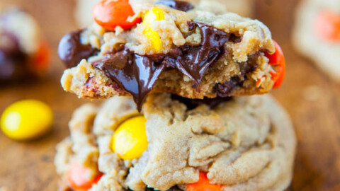 Stacked chocolate chip cookies with colorful candy pieces on a wooden surface.