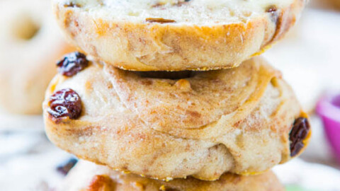 A stack of three bagels with raisins on a plate.