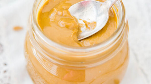 A jar of creamy peanut butter with a spoon inside it.