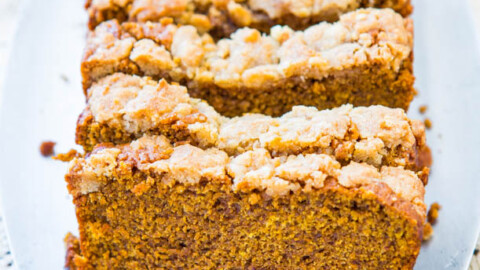 A freshly baked loaf of pumpkin bread with a streusel topping on a lace doily.