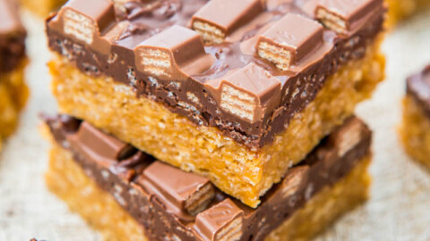 Stack of chocolate caramel slices on a textured surface.