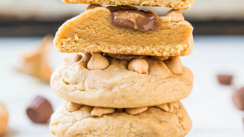 A stack of peanut butter cookies with chocolate pieces on a white surface.