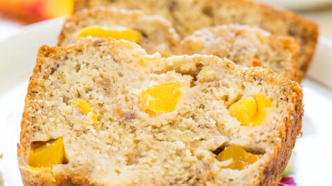 Sliced banana bread with peach pieces on a floral plate.