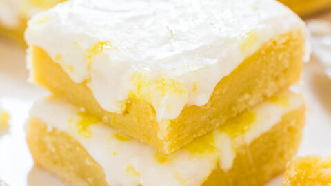 A close-up of a lemon bar with a dusting of powdered sugar on a plate.