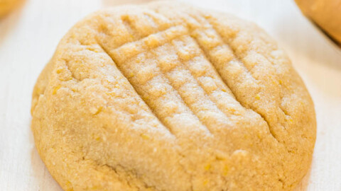 A freshly baked peanut butter cookie displayed on a light wooden surface.