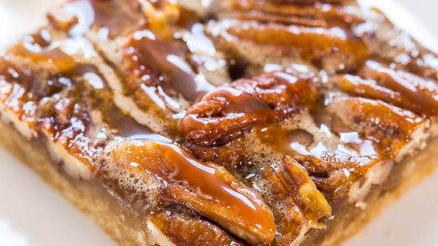 A close-up of a pecan bar with caramel topping and sea salt flakes.