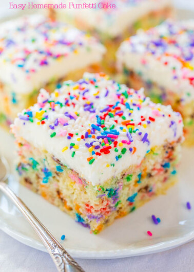 A slice of homemade funfetti cake with vanilla frosting and colorful sprinkles, presented on a white plate.