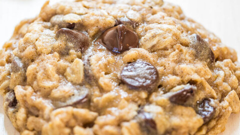 Freshly-baked chocolate chip cookie on a white surface.