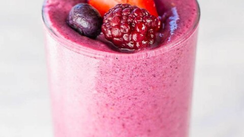 Berry smoothie topped with fresh strawberries, blueberries, and a raspberry.