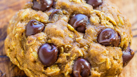 A close-up shot of a chocolate chip cookie on a wooden surface.