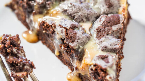 A slice of chocolate cookie pie with a melting scoop of ice cream on top, partially eaten with a fork on the side.