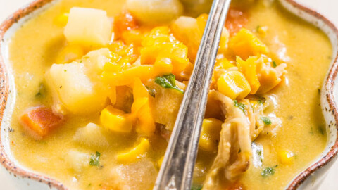 Bowl of chunky vegetable soup with a spoon.