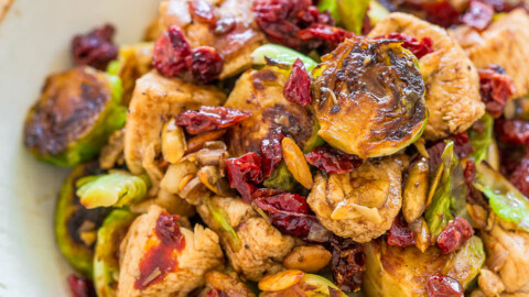 A bowl of roasted brussels sprouts and chicken with cranberries.