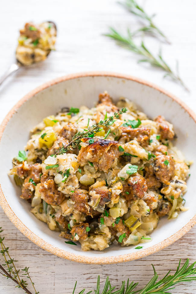 A bowl of stuffing garnished with fresh herbs on a wooden surface.