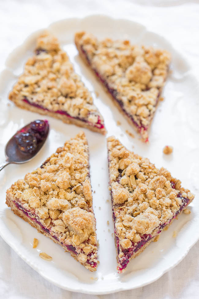 Three slices of crumb-topped pie on a white plate with a spoon and some filling on the side.