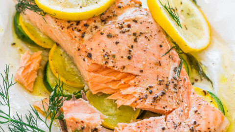 Baked salmon fillet with lemon slices and dill on a bed of zucchini.