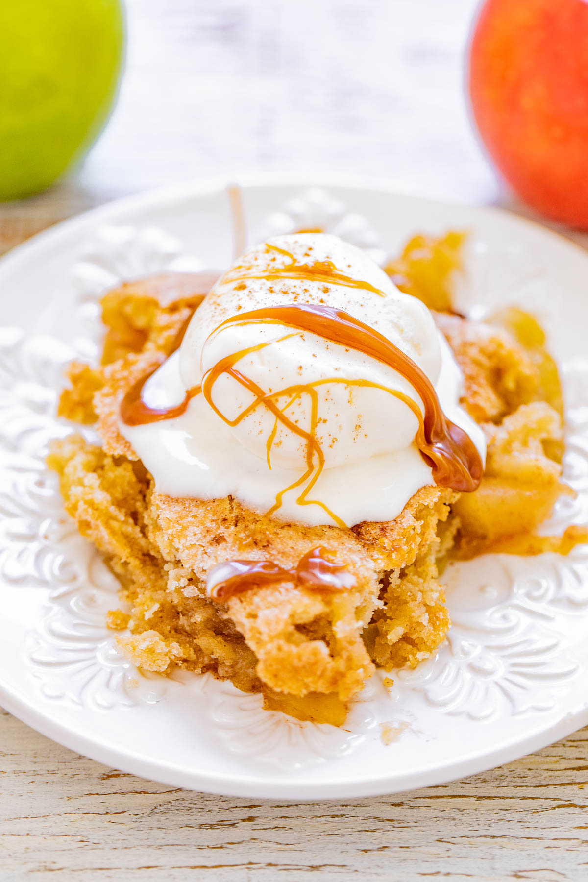 A plate of apple cobbler topped with a scoop of vanilla ice cream and drizzled with caramel sauce.