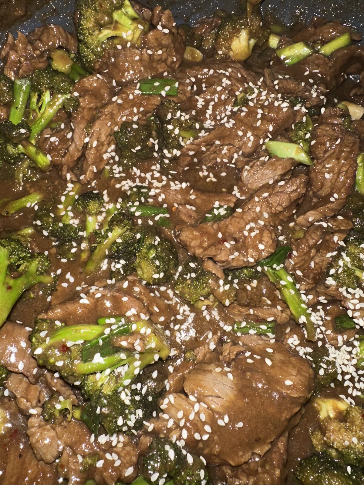 Beef and broccoli stir-fry garnished with sesame seeds in a savory sauce.