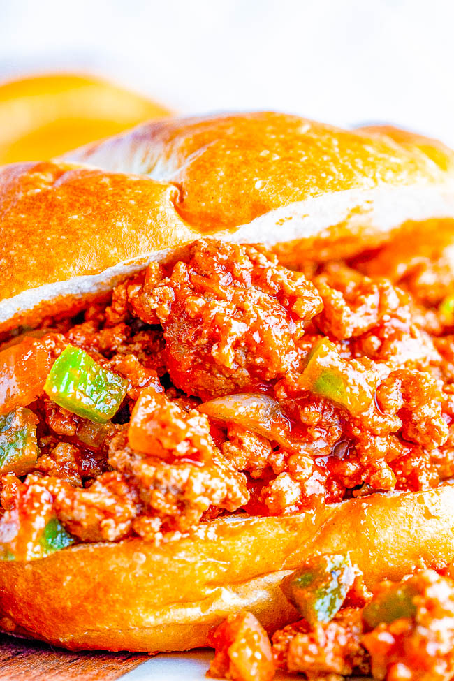 Close-up of a sloppy joe sandwich with seasoned ground meat and diced green peppers on a bun.