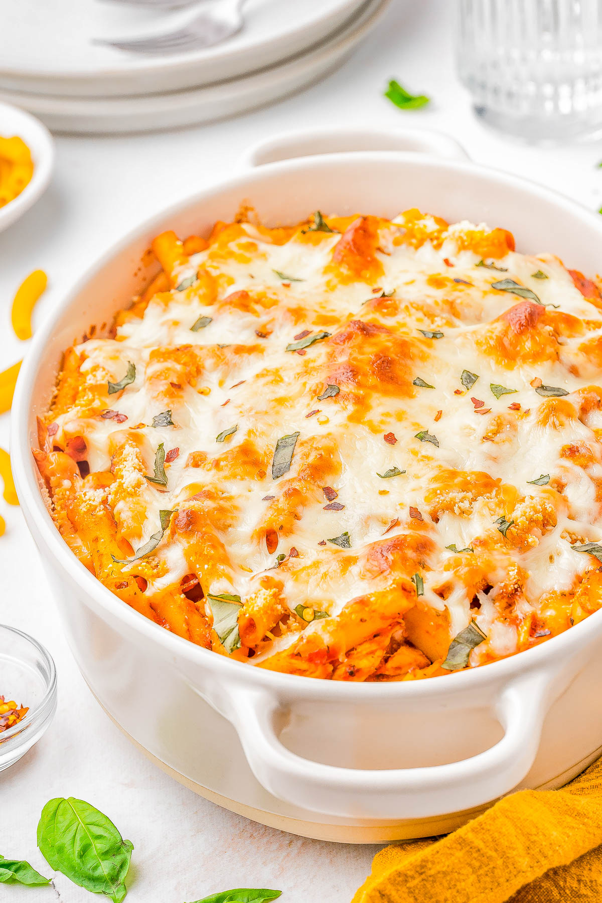 A round white dish filled with baked pasta topped with melted cheese and herbs.