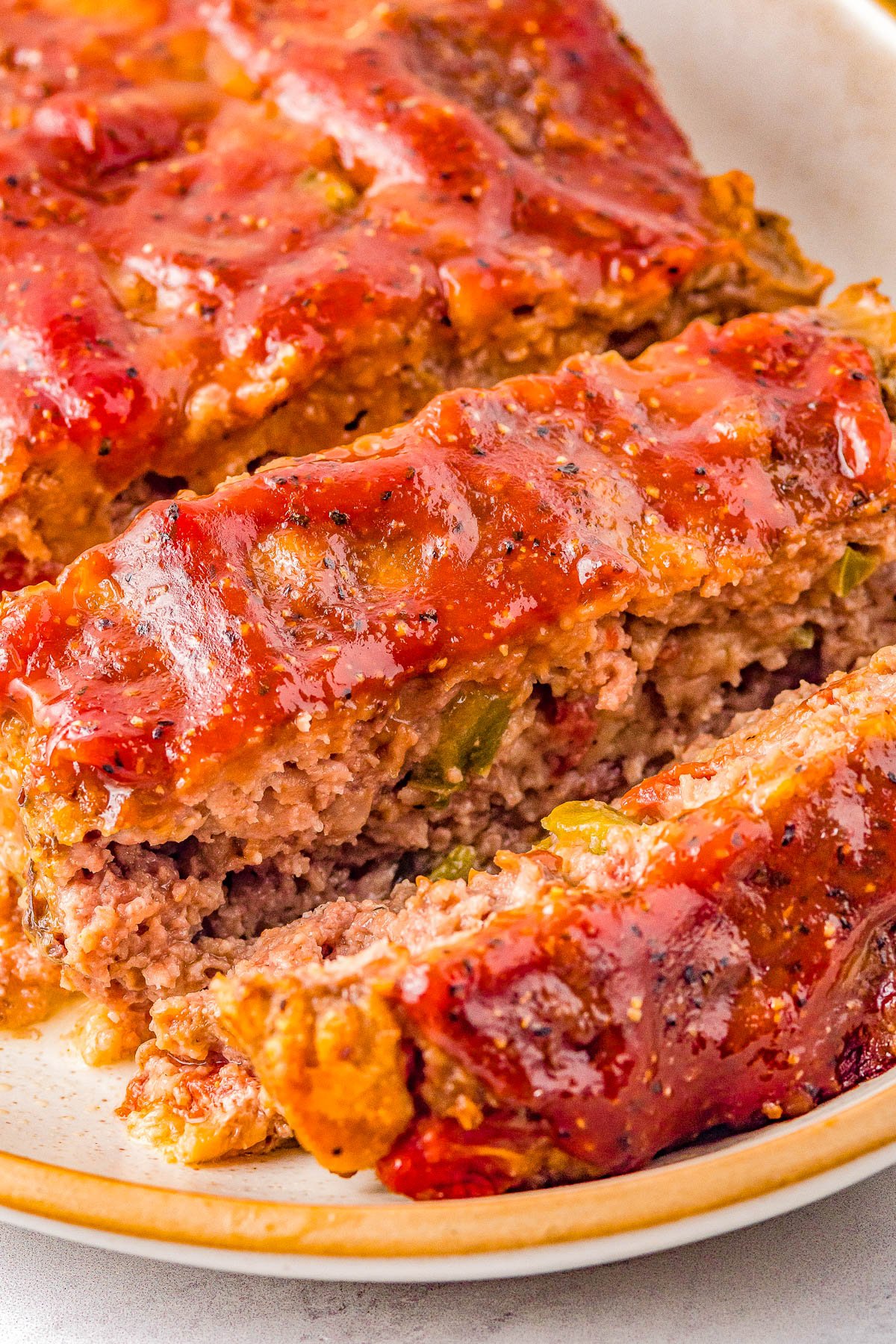 A plate with slices of meatloaf glazed with a red sauce.