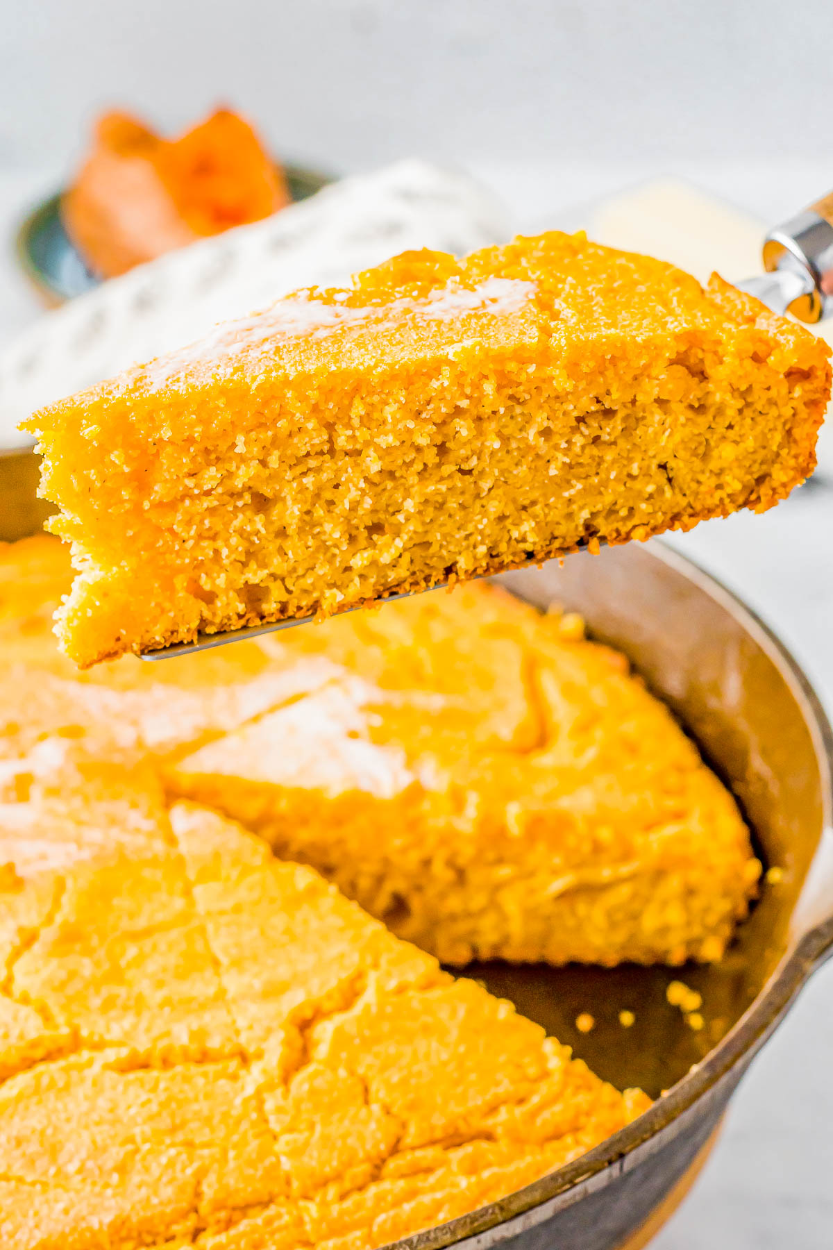 A slice of cornbread being lifted out of a pan.